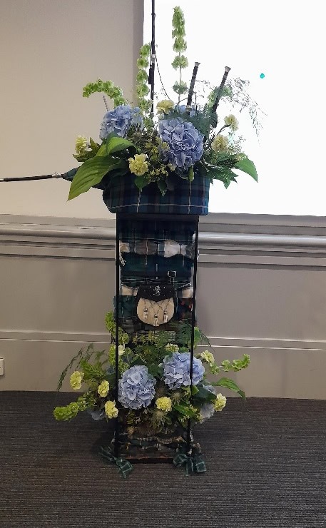 A clock with flowers in a basket Description automatically generated