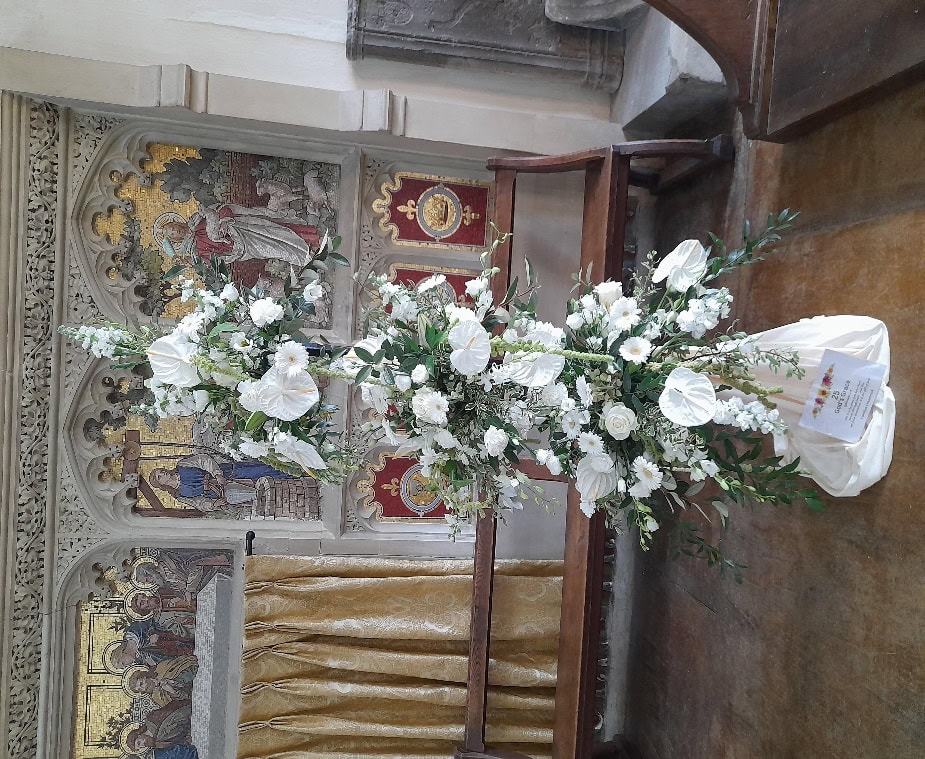 A large white flower arrangement in a church

Description automatically generated